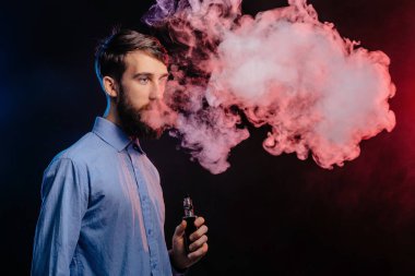 Genç adam bir sakal vaping ile ve Buhar bulutu serbest bırakır. hipster vaper duman Buharlaştırıcı.