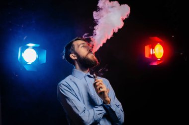 Genç adam bir sakal vaping ile ve Buhar bulutu serbest bırakır. hipster vaper duman Buharlaştırıcı.
