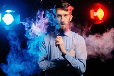 Genç adam bir sakal vaping ile ve Buhar bulutu serbest bırakır. hipster vaper duman Buharlaştırıcı.