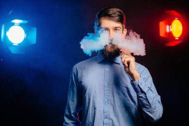 Genç adam bir sakal vaping ile ve Buhar bulutu serbest bırakır. hipster vaper duman Buharlaştırıcı.