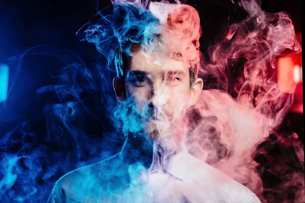 Un joven con barba vapeando y libera una nube de vapor. vaporizador de humo hipster vaper . — Foto de Stock