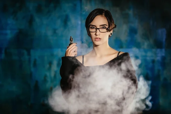 Dziewczyna z vaping okulary i wypuszcza chmurę pary wodnej. Model w internetowych czarny dym odparowalnik na turkus tło — Zdjęcie stockowe