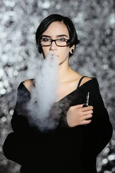 Dziewczyna z vaping okulary i wypuszcza chmurę pary wodnej. Model w odparowalnik internetowych czarny dym — Zdjęcie stockowe
