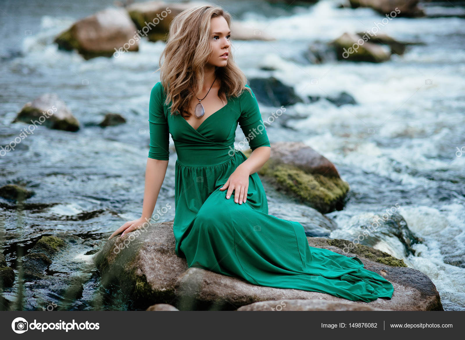 Beautiful girl posing on rocks near the Model in a green