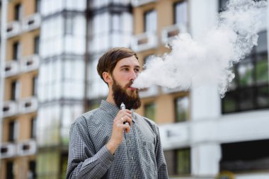 Sakal vaping elektronik sigara ile erkek modeli. Vaping açık havada. Güvenli yasaktır. Genç hippi vaper.