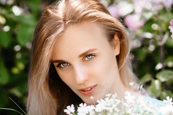 Blondynka z bukiet kwiaty dzikiego plenerze modelu w turkusową sukienkę na tle krzak bzu. — Zdjęcie stockowe