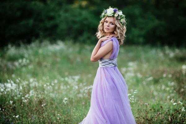 Frumusete femeie portret cu coroana de flori pe cap. mireasă în rochie violet în aer liber. soft focus — Fotografie, imagine de stoc