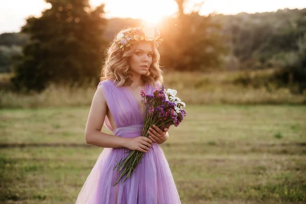 Портрет красивої жінки з вінок з квітами на голові на заході сонця. наречена в фіолетовій сукні на відкритому повітрі. м'який фокус — стокове фото