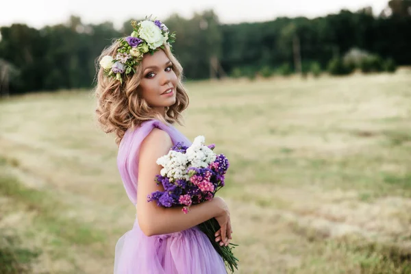 Schoonheid vrouw portret met krans van bloemen op hoofd bij zonsondergang. bruid in paarse jurk Outdoor. Soft Focus Sea... — Stockfoto