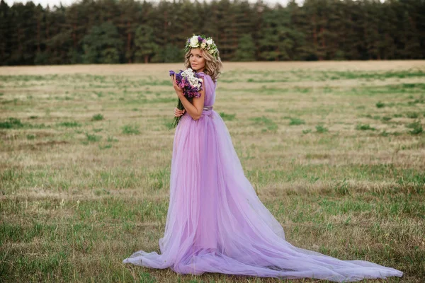 Портрет красивої жінки з вінок з квітами на голові на заході сонця. наречена в фіолетовій сукні на відкритому повітрі. м'який фокус — стокове фото