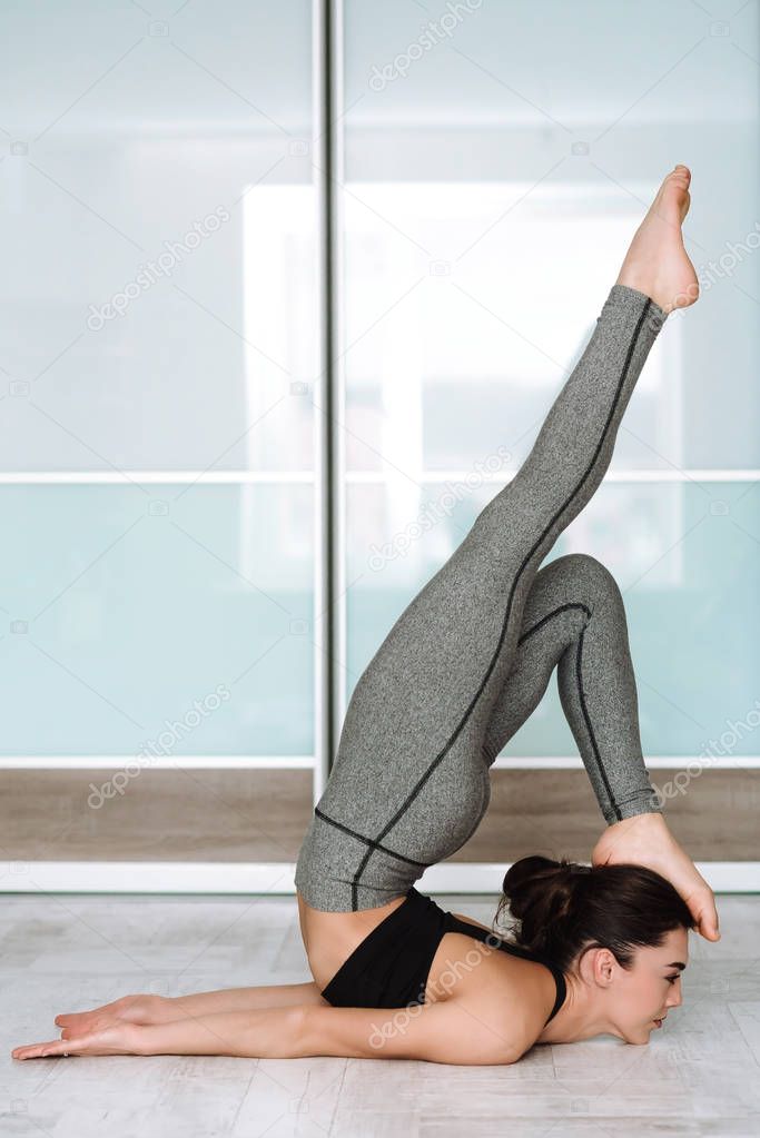 sports model girl doing asanas. beautiful brunette practicing yoga in the interior