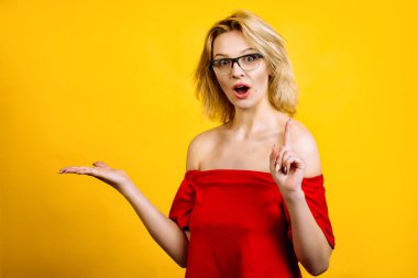 Genç bir kadın elleriyle kendini gösteriyor. Elleriyle poz veren gözlüklü güzel bir kız. Kırmızı bluzlu sarışın..