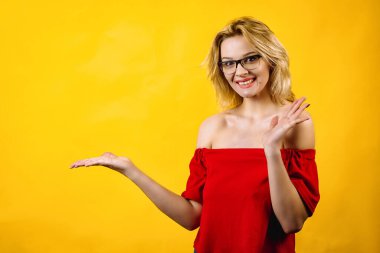 Genç bir kadın elleriyle kendini gösteriyor. Elleriyle poz veren gözlüklü güzel bir kız. Kırmızı bluzlu sarışın..