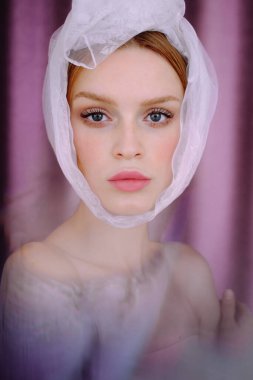 Pembe arka planda bir kızın portresi. Beyaz fularlı genç bir kadın.