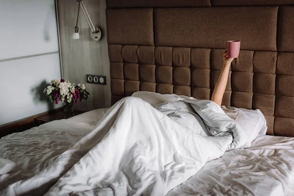 Kobieta Łóżku Pod Kocem Podniesionymi Rękami Trzymająca Filiżankę Kawy Poranny Zdjęcia Stockowe bez tantiem
