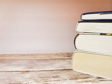 Tahta bir masa ve beyaz arka plan üzerinde dört kitap yığını yakın plan. Mesajın için yer aç. Tonlama ile resim.