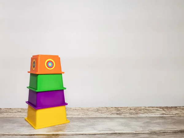 Educational toy for children - multi-colored pyramid on a wooden table and white background. Space for your text.