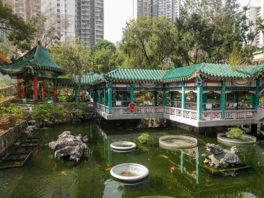 Wong Tai Sin tapınağında iyi dilekler bahçesi. Çin usulü köprüleri olan pagodalar ve büyük kırmızı balıklı bir gölet..