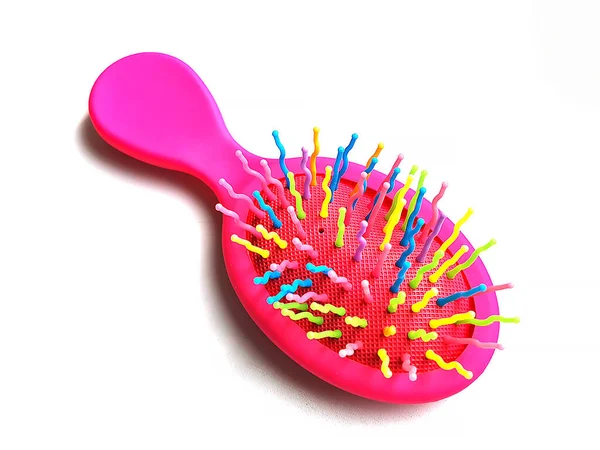 Çocukların parlak pembe saç fırçası ya da beyaz arka planda masaj tarağı. Saç bakımı ve oyunlar için çocuk aksesuarı.