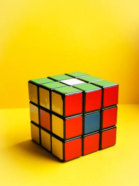 Sarı arka planda Rubik Küpü. Dikey görüntü. Yüz renkleri: kırmızı, yeşil, sarı. Klasik bir şey..