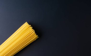 Çiğ spagetti paketlenmiş ve siyah arkaplanda sergilenmiş.