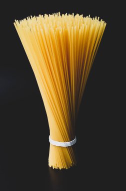 Siyah arka planda bağlanmış çiğ spagetti.