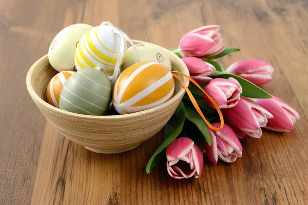 Easter eggs in cup with bunch of pink tulips wooden background — Stock Photo, Image