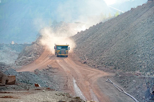 Dumper truck driving in an active quarry mine of porphyry rocks. — Stock Photo, Image