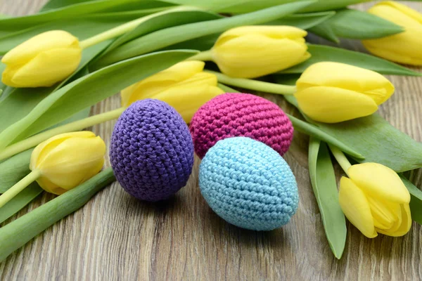crocheted easter eggs and a boquet of yellow tulips