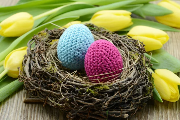 Crocheted easter eggs and a boquet of yellow tulips — Stock Photo, Image