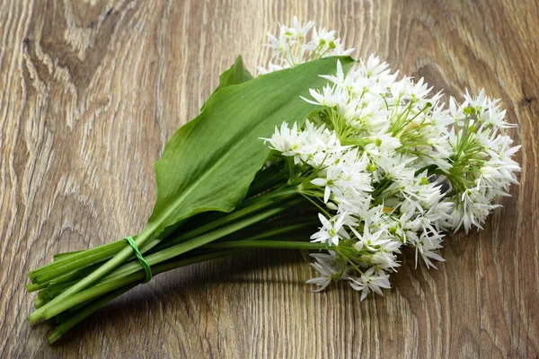 Bund Bärlauch Blütenköpfe und Blätter auf hölzernen Ta — Stockfoto