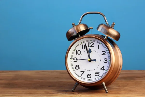 Bronce un retro un reloj despertador sobre un fondo azul . — Foto de Stock