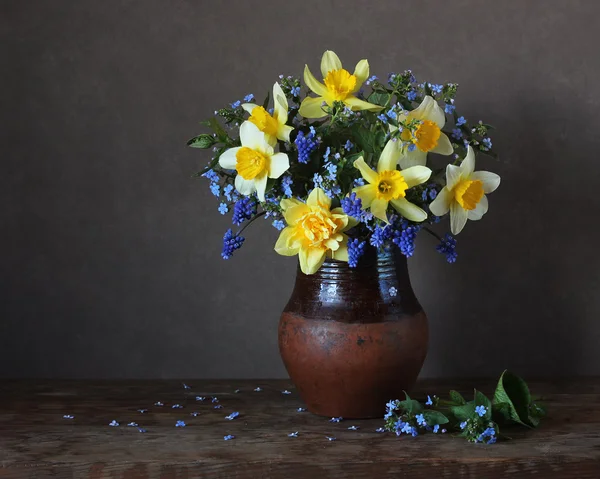 Buquê de narcisos e não me esqueça em um jarro de barro . — Fotografia de Stock