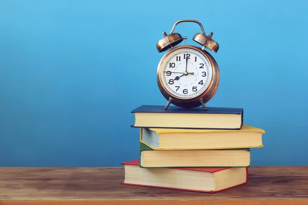 本と青い背景に目覚まし時計。学校に戻る. — ストック写真