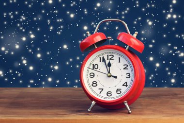 Saat on iki yönünde uçan kar ortasında kırmızı retro çalar saat.