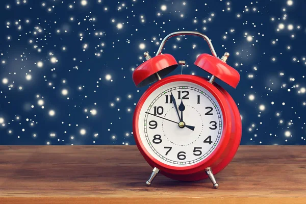 Saat on iki yönünde uçan kar ortasında kırmızı retro çalar saat.