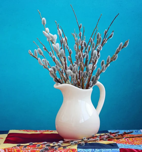 Bodegón con ramas de sauce en una jarra blanca sobre un fondo azul — Foto de Stock