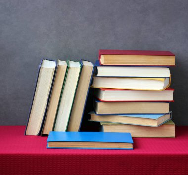 Kırmızı bir masa örtüsü ile masada kitap yığını.