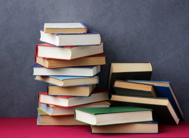 Kırmızı bir masa örtüsü ile masada kitap yığını.