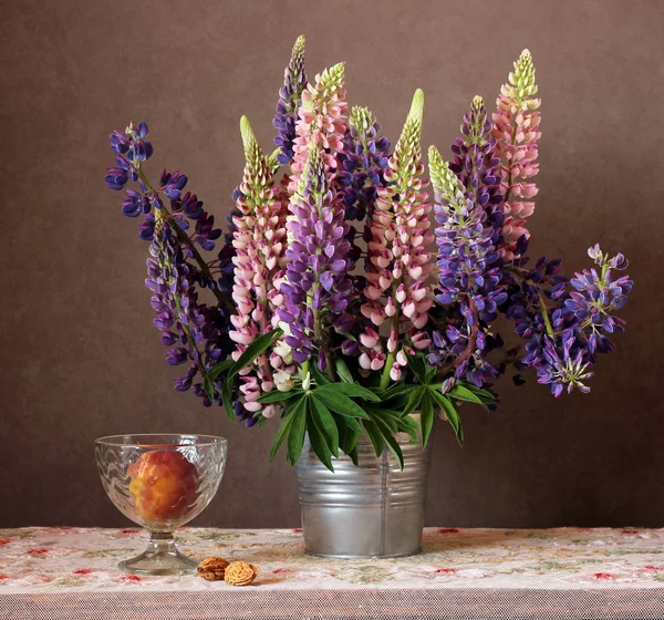 Натюрморт с люпинами и персиком в вазе . — стоковое фото