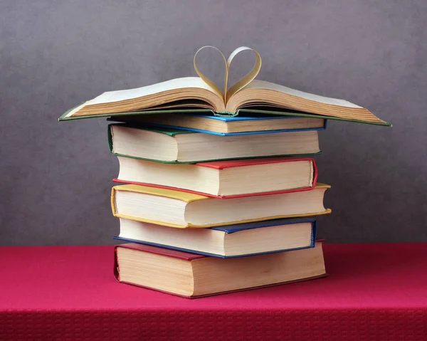 Pilha de livros na mesa, um livro aberto no topo . — Fotografia de Stock