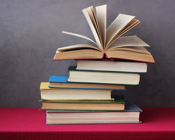 Montón de libros sobre la mesa con un mantel rojo . — Foto de Stock