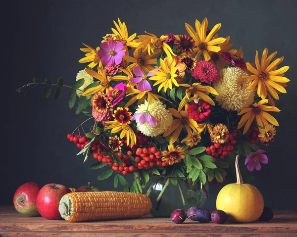 Autumn flowers in jug, fruit and vegetables on the table — Stock Photo, Image