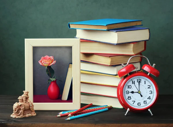 Stilleven met boeken, een wekker en een frame voor een foto. — Stockfoto