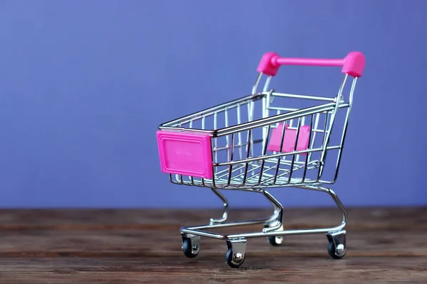Игрушечный мини-тележка для супермаркета на фиолетовом фоне . — стоковое фото