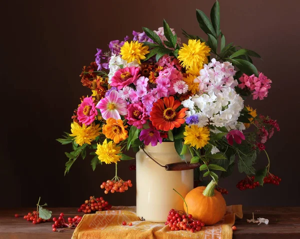 Land bloemen in kunnen op de tafel, pompoen en bessen. — Stockfoto