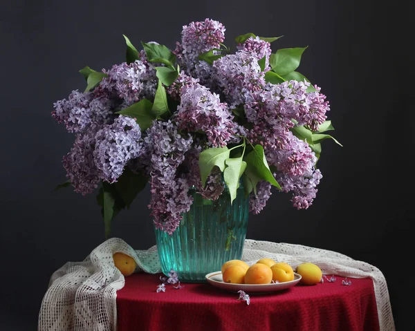 Kytice fialová lila v modrou vázu a meruňky — Stock fotografie