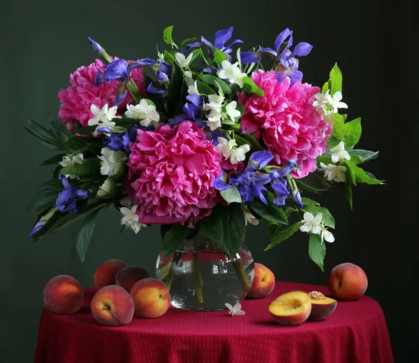 Букет культивируемых цветов в кувшине и персиках . — стоковое фото