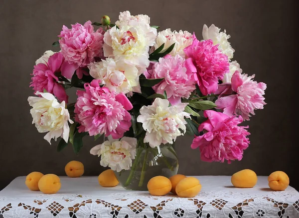 Roze en witte pioenrozen. Bloemen in een vaas en abrikozen op de ta — Stockfoto