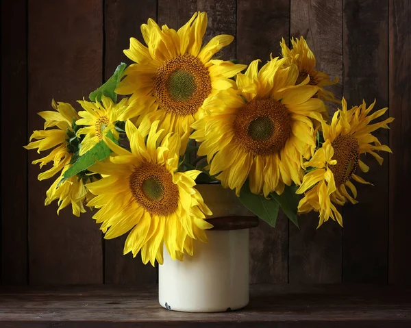 Boeket van zonnebloemen in een blikje op een donkere achtergrond. — Stockfoto